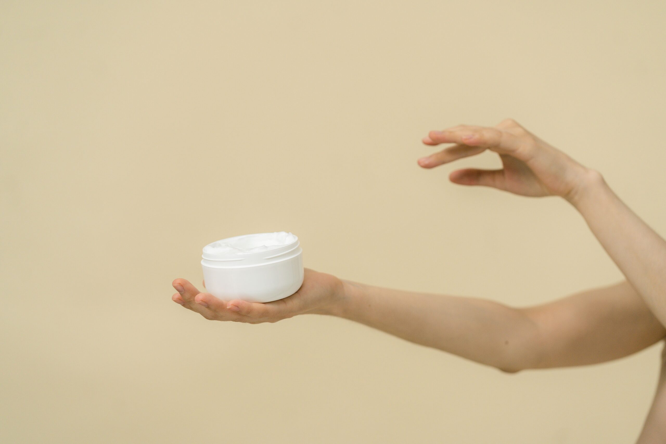 Blank cream jar held for hygienic packaging and sample review