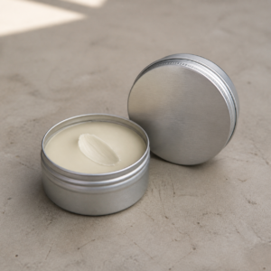 Unbranded beard styling balm tin and ivory formula sample on a cosmetics development table