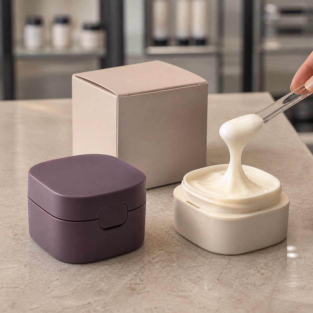 Muted plum outer jar oat ivory refill cup and elastic feel cream texture on a cosmetics sample table