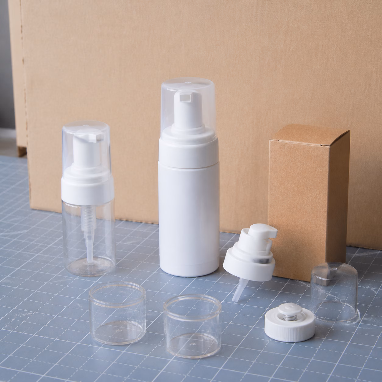 Blank mechanical foamer bottles, compact pump, cap components, sample cups and carton arranged for private label packaging review