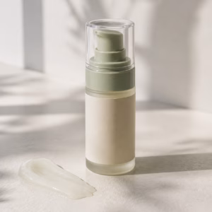 Unbranded sage airless hand serum pump sample with a translucent lightweight texture swipe on a neutral table
